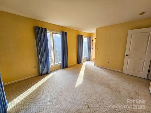 empty room featuring light carpet and baseboards