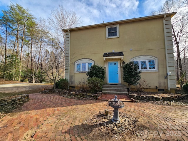 view of front facade featuring entry steps, crawl space, and stucco siding