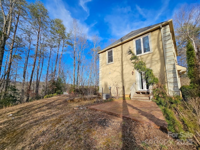 view of side of home with central AC and stucco siding