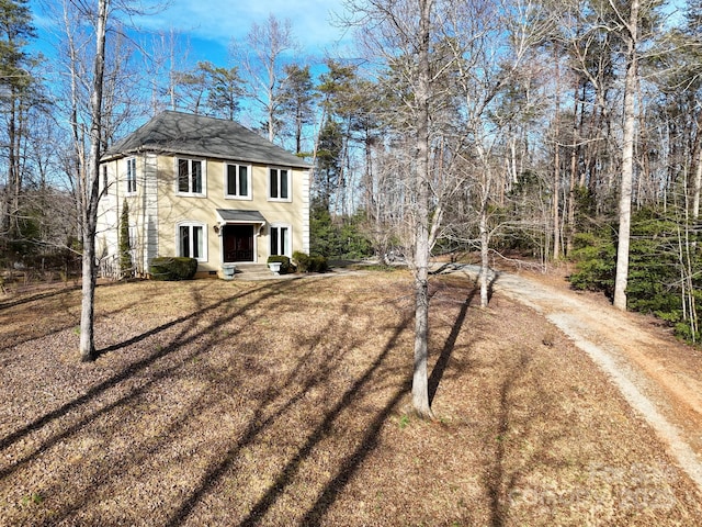 view of front of home with dirt driveway and stucco siding