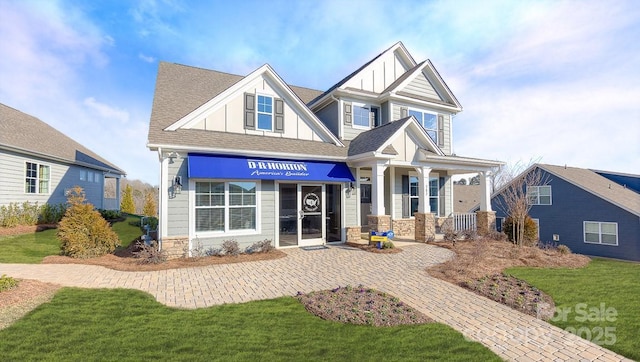 craftsman-style home featuring roof with shingles, a front yard, and board and batten siding