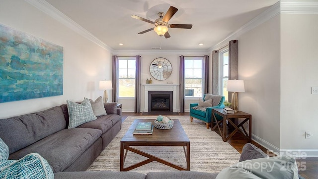 living area with a fireplace, crown molding, ceiling fan, wood finished floors, and baseboards