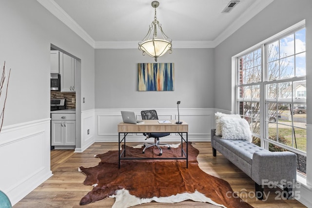 office featuring visible vents, a wainscoted wall, crown molding, and light wood finished floors