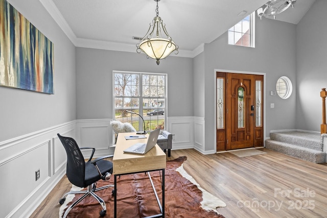 home office with a wainscoted wall, visible vents, wood finished floors, crown molding, and lofted ceiling