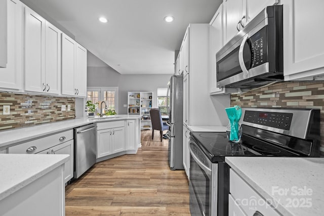 kitchen featuring a sink, recessed lighting, light wood-style floors, appliances with stainless steel finishes, and white cabinets