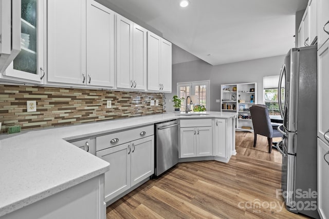 kitchen featuring white cabinets, a peninsula, stainless steel appliances, and a sink