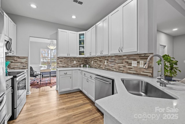 kitchen with a sink, white cabinetry, light wood finished floors, and stainless steel appliances