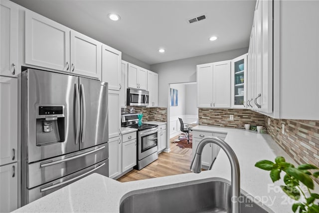 kitchen featuring visible vents, a sink, white cabinets, appliances with stainless steel finishes, and tasteful backsplash