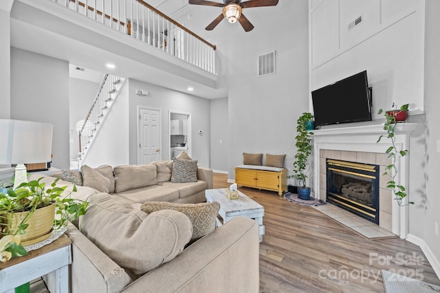 living room with visible vents, wood finished floors, stairs, and a tiled fireplace