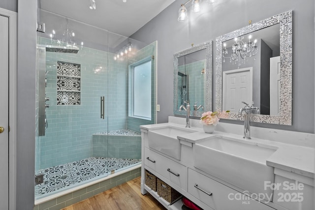 full bath featuring a sink, double vanity, wood finished floors, and a shower stall