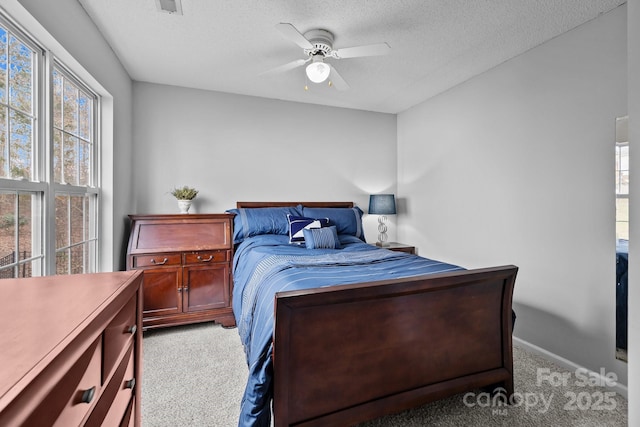 bedroom featuring multiple windows, a textured ceiling, ceiling fan, and carpet flooring