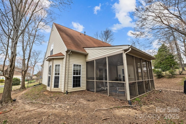 rear view of house with fence and a sunroom