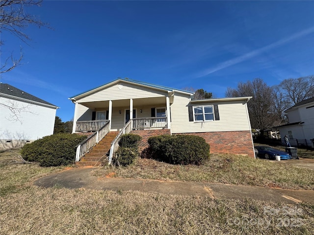 view of front of house with brick siding, stairway, and a porch