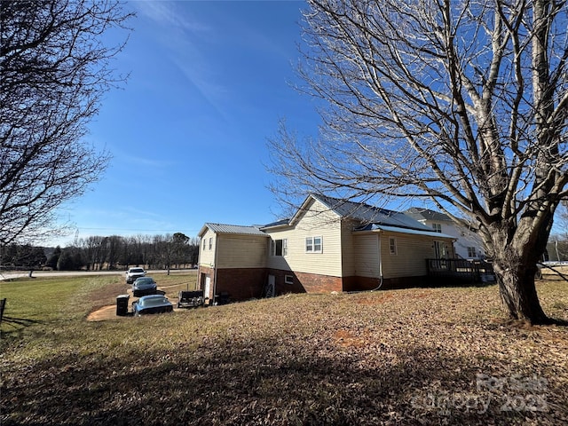 view of side of home featuring a lawn and a deck