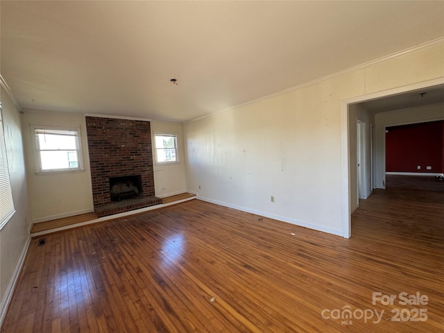 unfurnished living room with crown molding, plenty of natural light, baseboards, and wood-type flooring