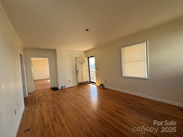 spare room featuring baseboards, hardwood / wood-style floors, and crown molding