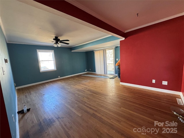 empty room with wood finished floors, baseboards, and ornamental molding