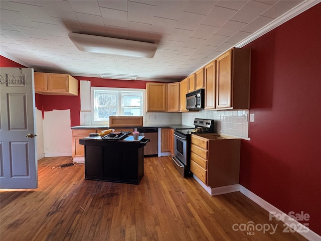 kitchen featuring backsplash, a kitchen island, baseboards, dark wood-style floors, and stainless steel appliances