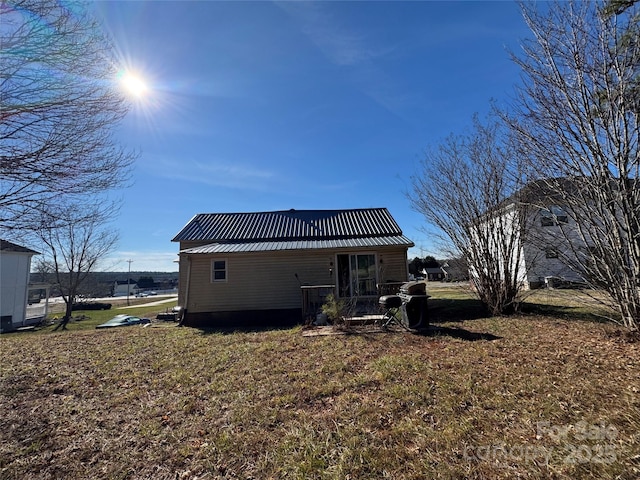 rear view of property with metal roof and a yard