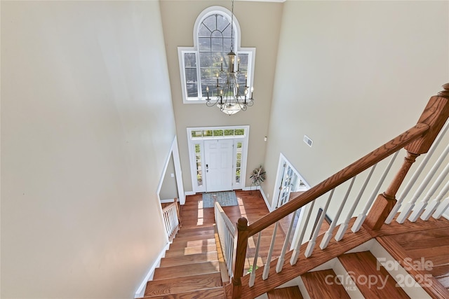 foyer with a notable chandelier, a high ceiling, wood finished floors, baseboards, and stairs