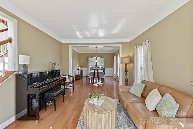 living area with crown molding, wood finished floors, and wainscoting