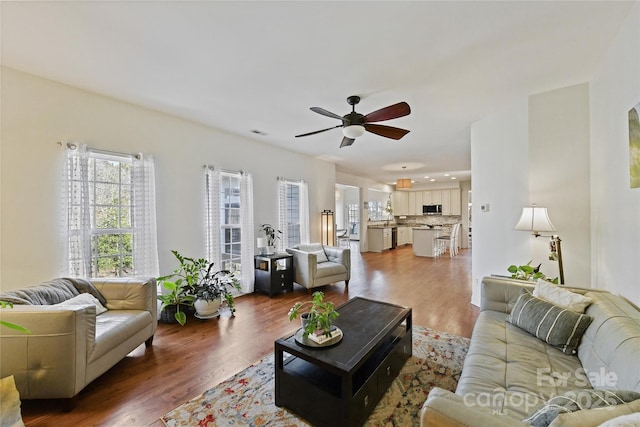 living area with ceiling fan, visible vents, and wood finished floors