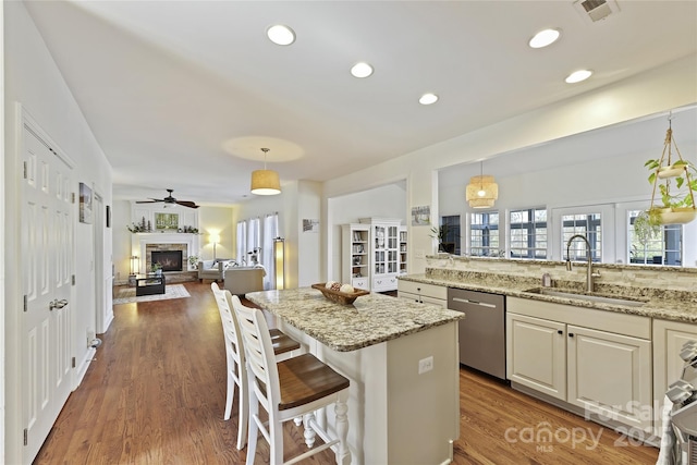 kitchen with visible vents, dishwasher, open floor plan, wood finished floors, and hanging light fixtures