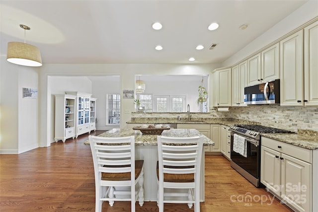 kitchen with stainless steel appliances, visible vents, a sink, and light wood finished floors