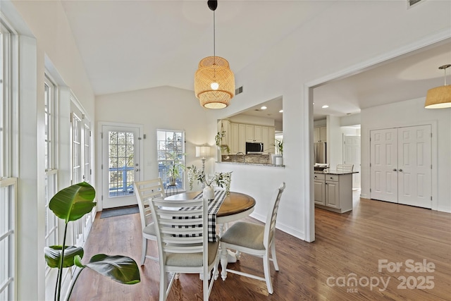 dining room with lofted ceiling, visible vents, baseboards, and wood finished floors