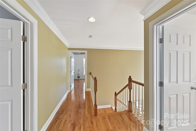 corridor with visible vents, an upstairs landing, baseboards, ornamental molding, and light wood-type flooring