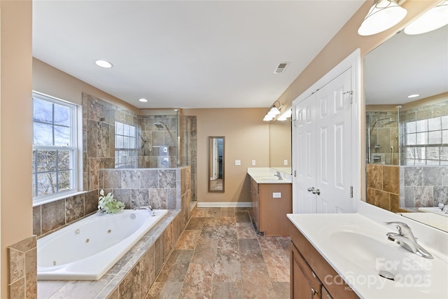 bathroom featuring a stall shower, visible vents, two vanities, a jetted tub, and a sink