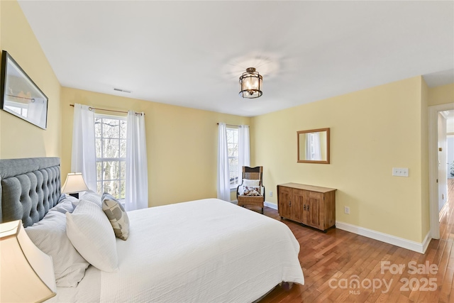 bedroom featuring visible vents, baseboards, and wood finished floors