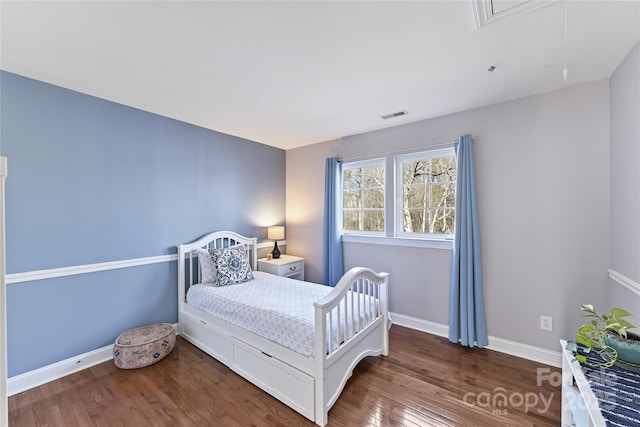 bedroom featuring attic access, visible vents, baseboards, and wood finished floors