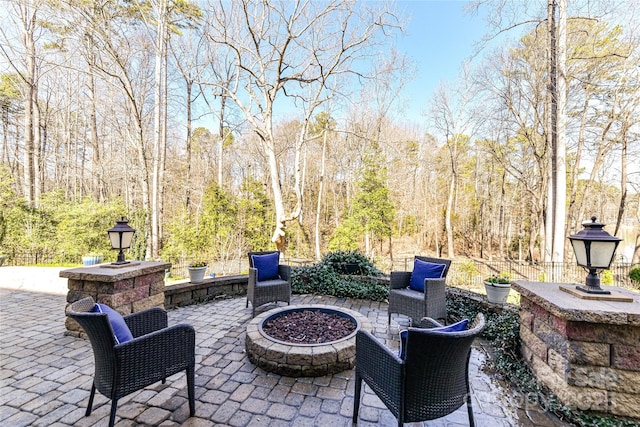 view of patio featuring a forest view and an outdoor fire pit