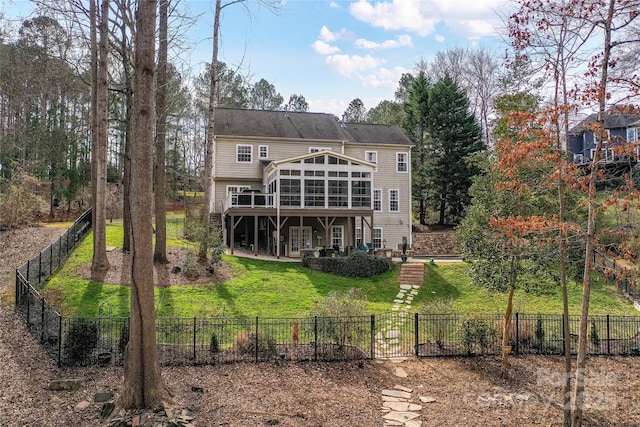 back of property featuring a wooden deck, a lawn, a fenced backyard, and a sunroom