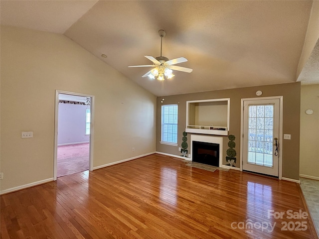 unfurnished living room with a fireplace with flush hearth, a healthy amount of sunlight, ceiling fan, and wood finished floors