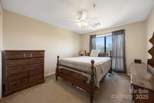 bedroom with a textured ceiling, light colored carpet, a ceiling fan, baseboards, and visible vents