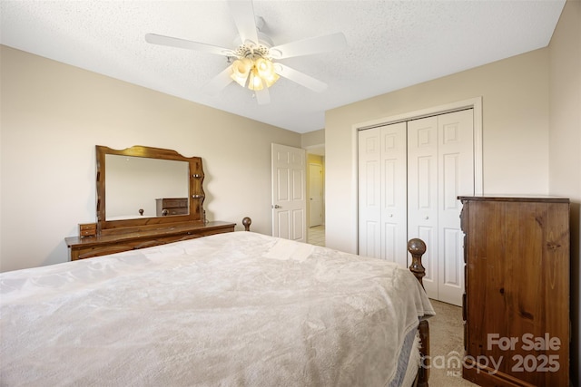 bedroom with carpet, a textured ceiling, a ceiling fan, and a closet