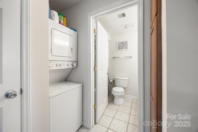 laundry area with stacked washing maching and dryer, laundry area, visible vents, and a textured ceiling