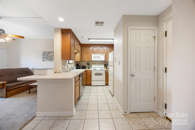 kitchen with a peninsula, white appliances, visible vents, a ceiling fan, and light countertops