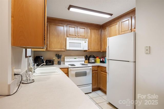 kitchen featuring white appliances, light tile patterned floors, light countertops, and a sink