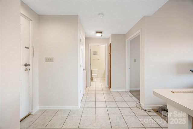 hall with baseboards and light tile patterned floors