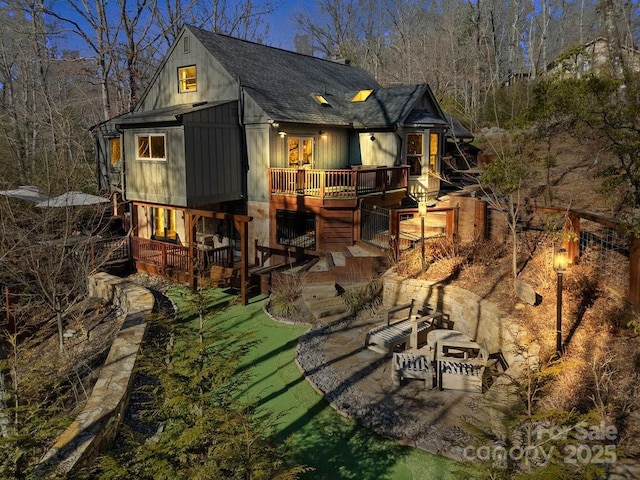 back of property featuring a shingled roof, a patio, and a wooden deck