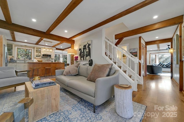 living area with stairway, beamed ceiling, wood finished floors, and recessed lighting