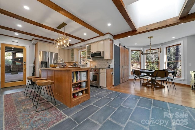 kitchen with a center island, backsplash, a barn door, appliances with stainless steel finishes, and butcher block countertops