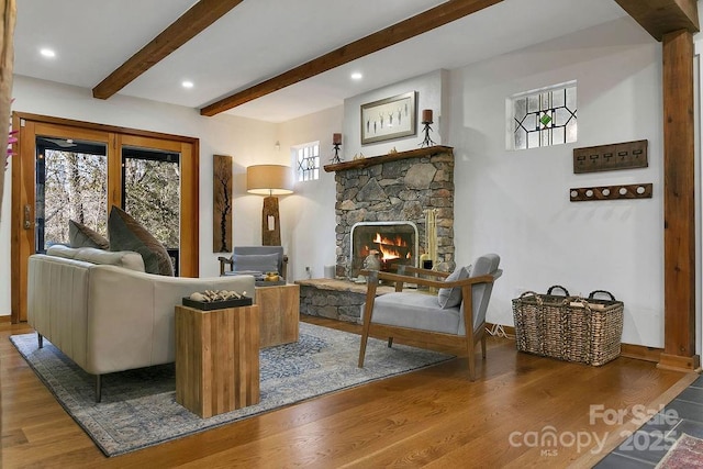 sitting room featuring baseboards, a fireplace, beamed ceiling, and wood finished floors