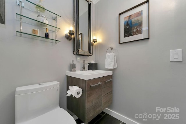 bathroom with baseboards, vanity, toilet, and tile patterned floors