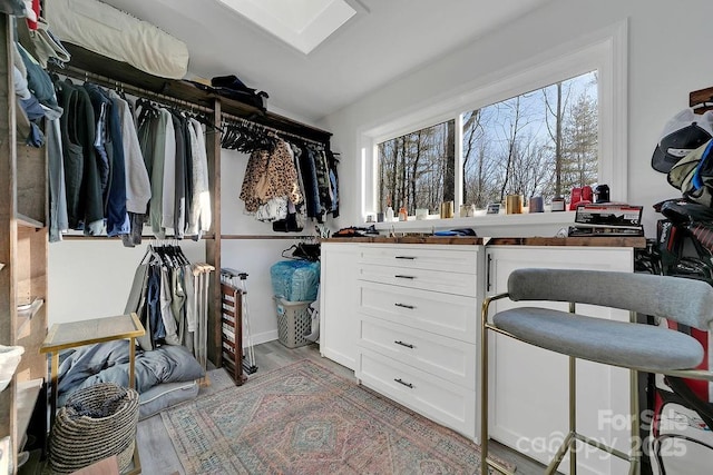 walk in closet with a skylight and light wood-style flooring