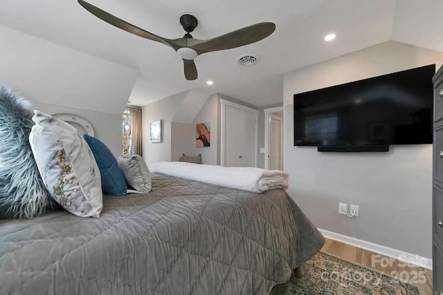 bedroom featuring lofted ceiling, a ceiling fan, visible vents, and wood finished floors