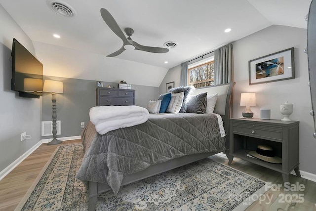 bedroom with lofted ceiling, wood finished floors, visible vents, and baseboards